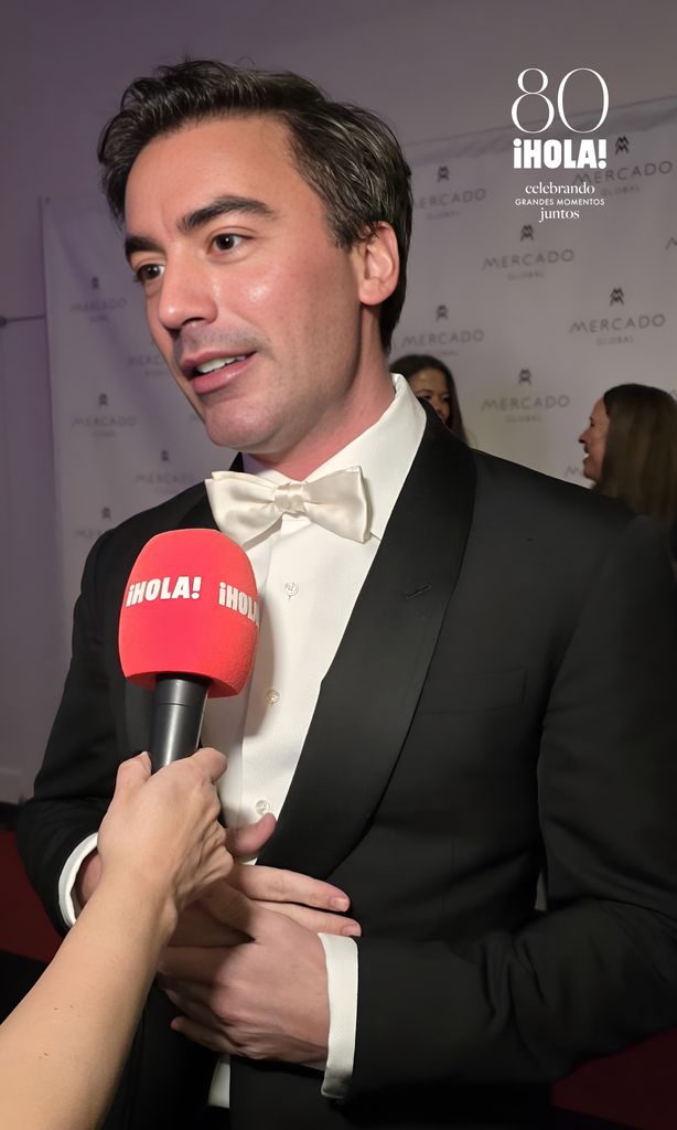 Fernando García, diseñador de moda, vestido con un esmoquin negro y pajarita blanca, siendo entrevistado en la alfombra roja de la Gala Fashion Forward de Mercado Global