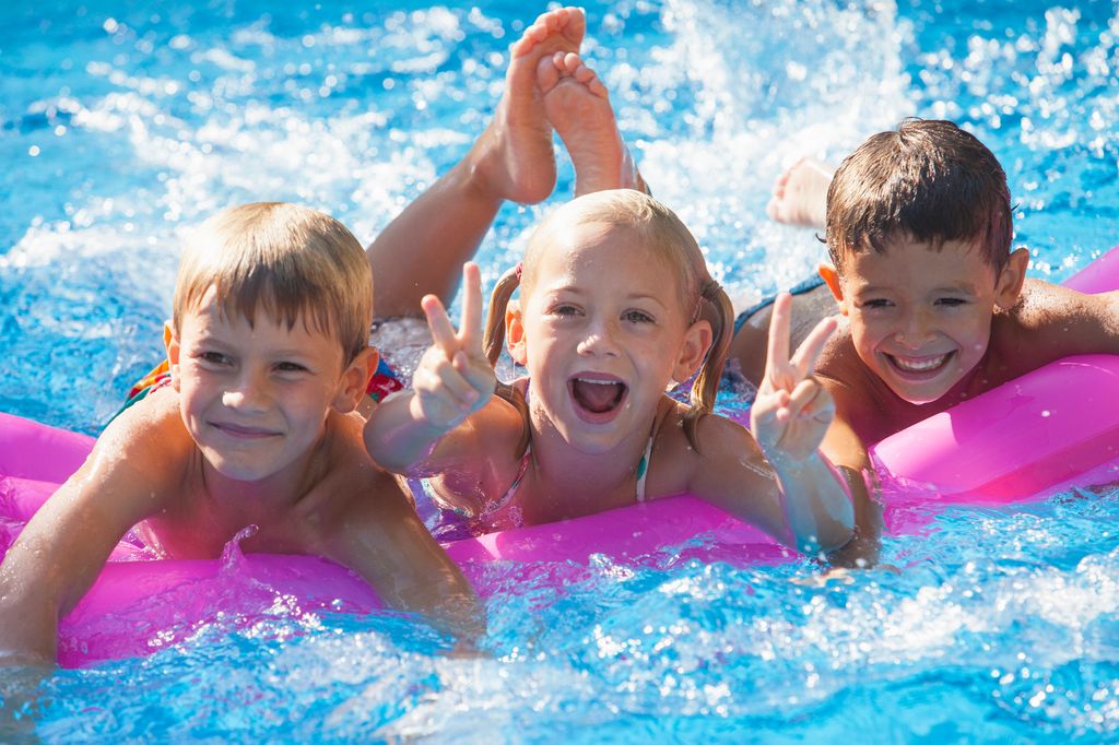 tres niños en la piscina disfrutando del verano
