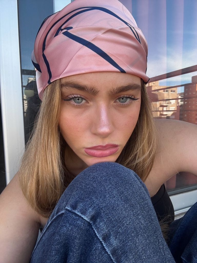Cami Yavicoli con pañuelo en la cabeza rosa con rayas azules, pelo suelto y maquillaje natural
