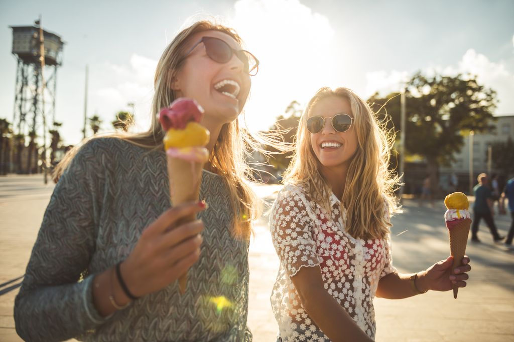 Dos mujeres con gafas de sol disfrutando de helados en un día soleado.