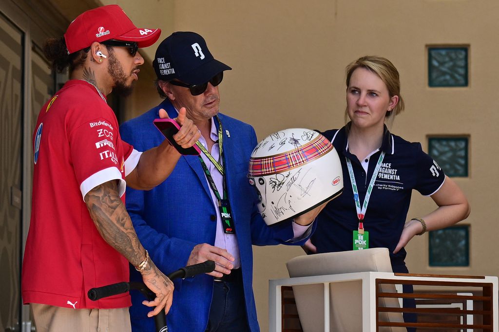 Mark Stewart, the son of former British racing driver Jackie Stewart, holds his father's old helmet as he talks to Ferrari's British driver Lewis Hamilton before the third practice session ahead of the Bahrain Formula One Grand Prix at the Bahrain International Circuit in Sakhir on April 12, 2025. (Photo by Andrej ISAKOVIC / AFP) (Photo by ANDREJ ISAKOVIC/AFP via Getty Images)          