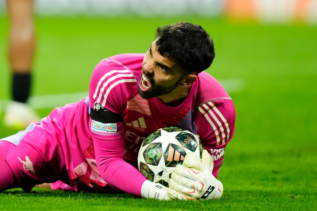 David Raya, sobre el césped, ataja el balón durante el Real Madrid-Arsenal 