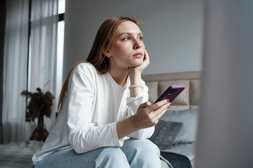 Chica triste con un móvil en la mano