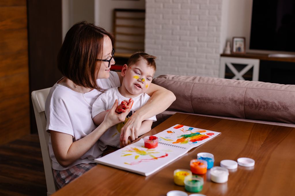 Madre pintando con su hijo con discapacidad