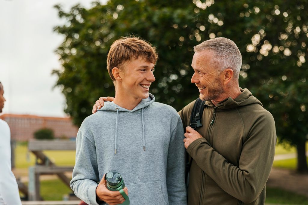 padre e hijo adolescente sonrientes, al aire libre