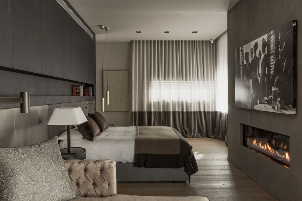 Dormitorio con chimenea y hasta un rincón de sofá para el relax durante el día