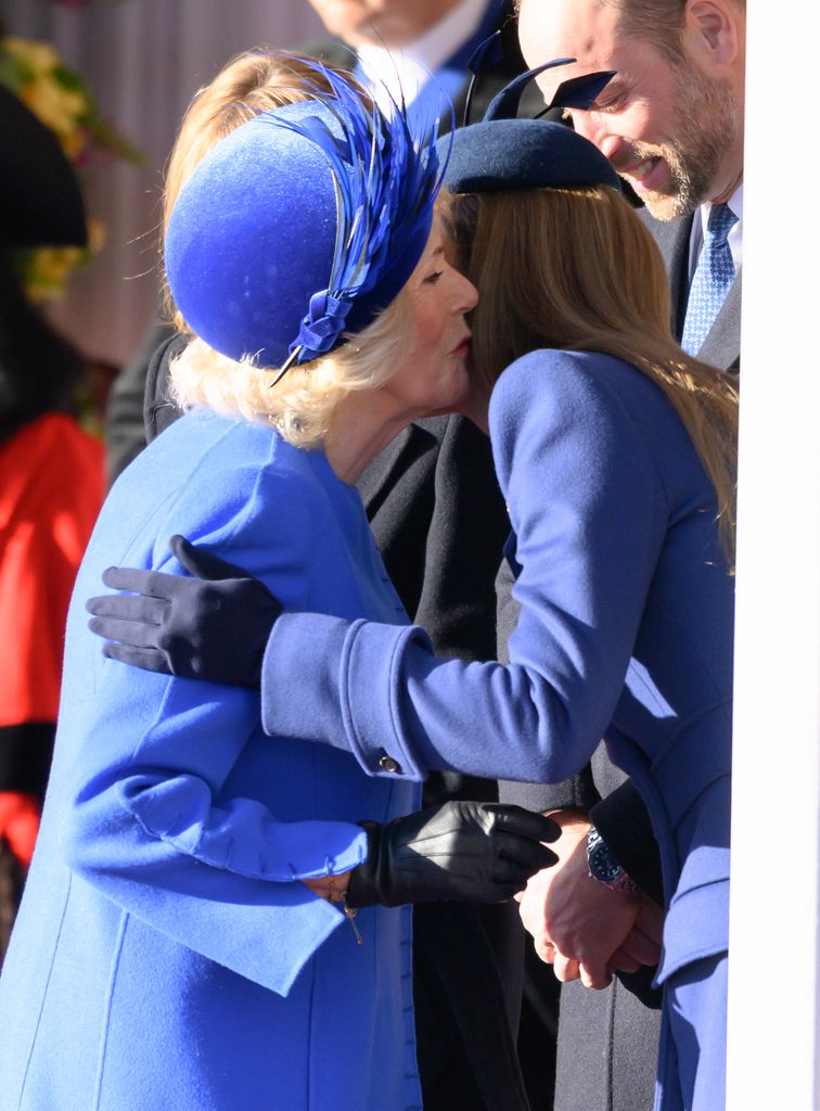 La reina Camilla y la princesa Kate saludándose efusivamente con un beso en la mejilla y un abrazo fraternal.