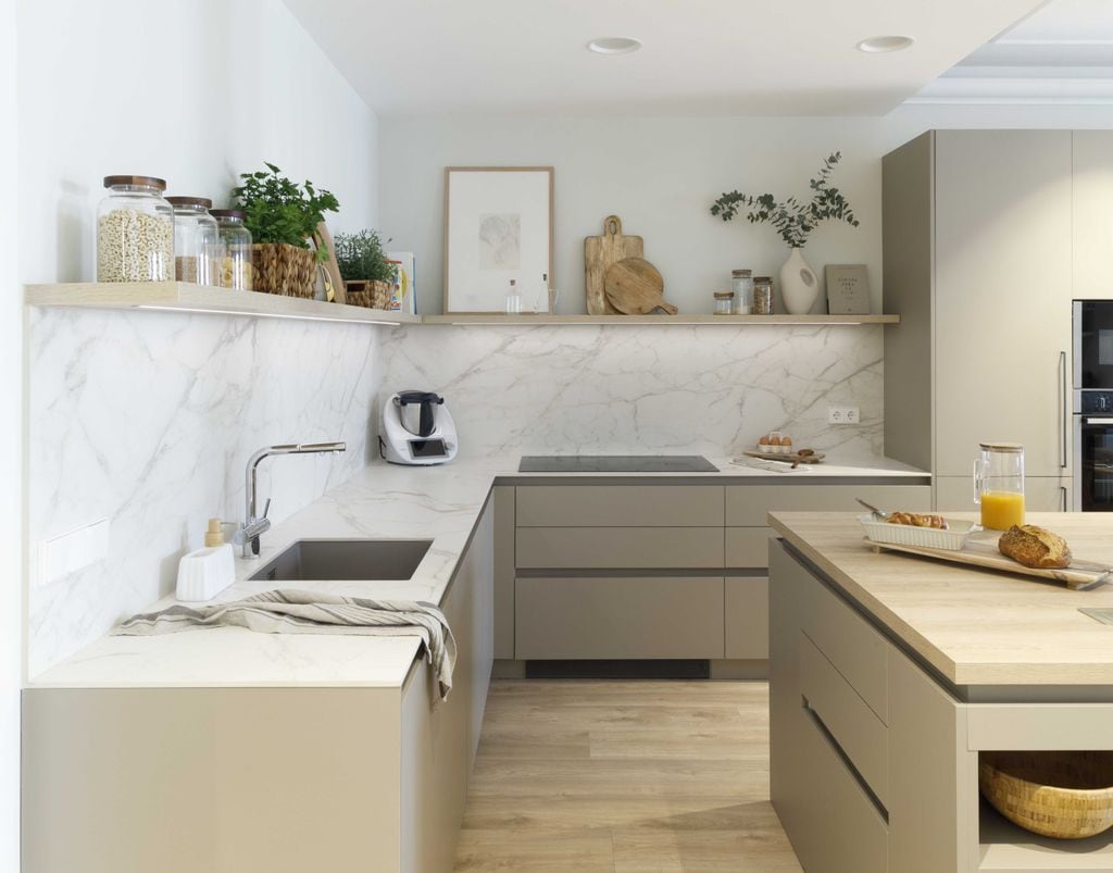 Cocina con muebles beige y encimera y antepecho con acabado mármol.