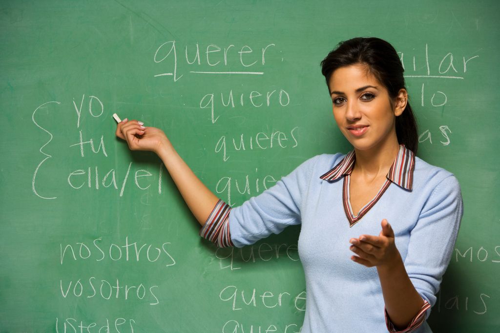 profesora con una pizarra detrás dando clases de español