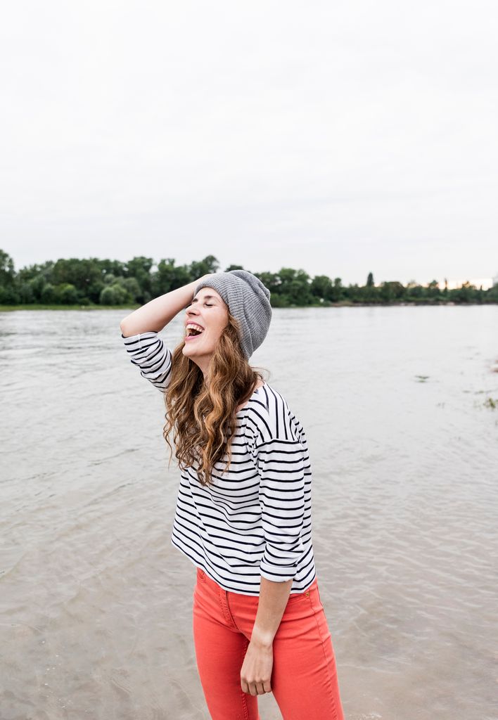 mujer riéndose junto a un lago