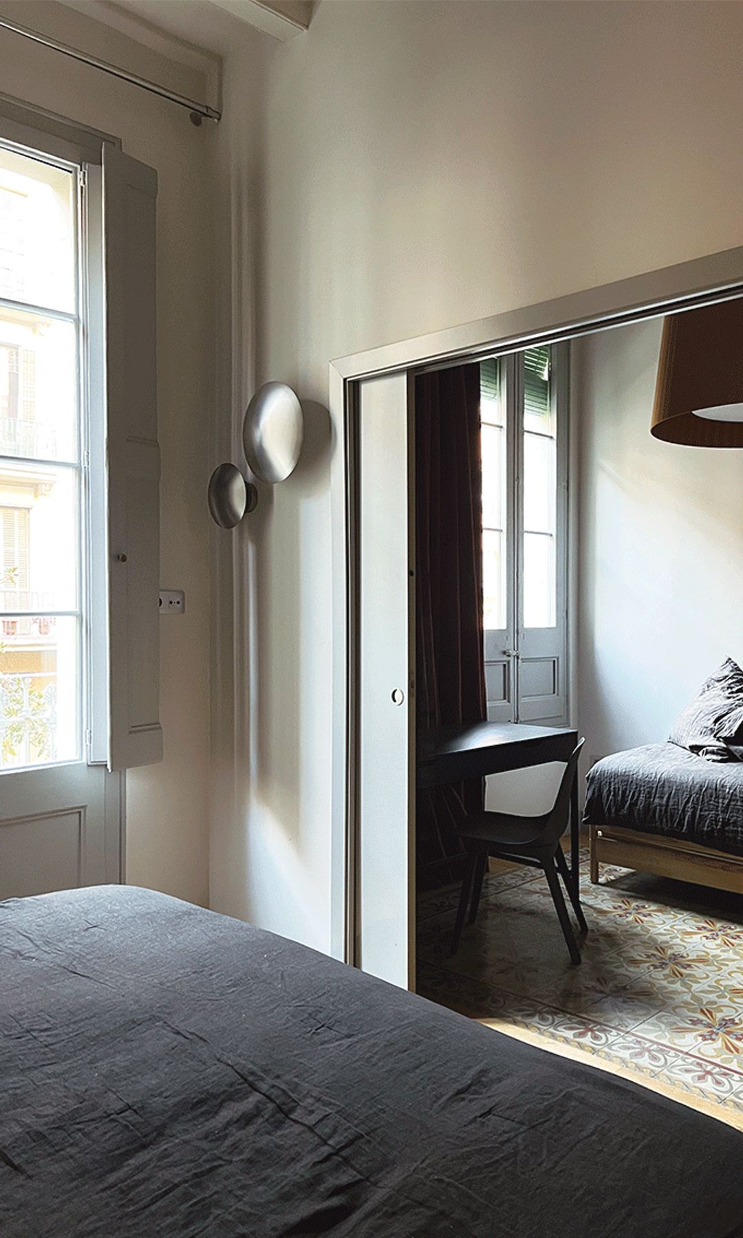Dormitorio con puerta corredera, grandes ventanales antiguos, suelo hidráulico, apliques de pared, puerta corredera