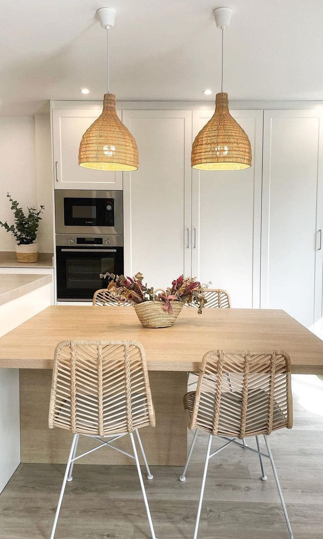 Cocina con office, muebles blancos, mesa de madera, sillas de fibras vegetales, lámparas de techo de fibras vegetales