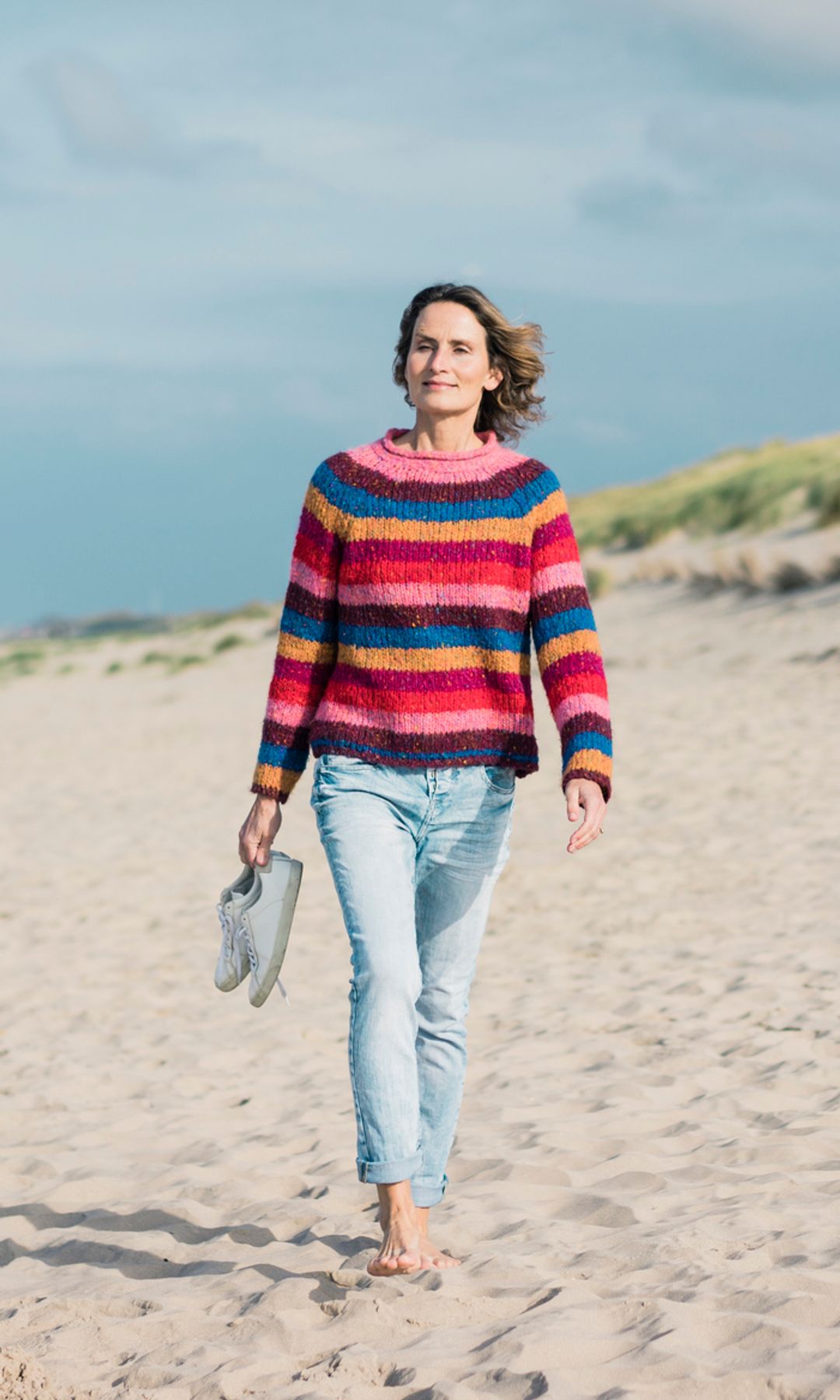 mujer madura caminando sobre la arena de la playa