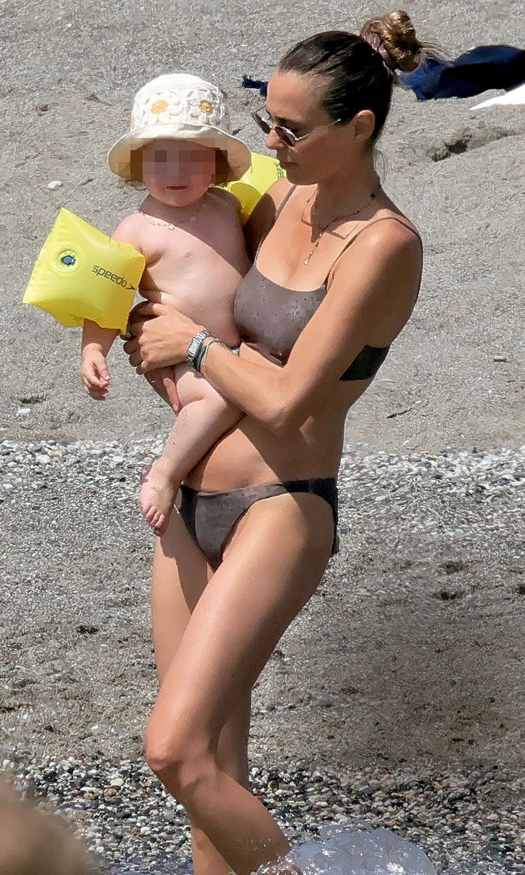 Claudia, en plena forma en bikini, lleva en brazos a la pequeña de sus hijas, Violeta