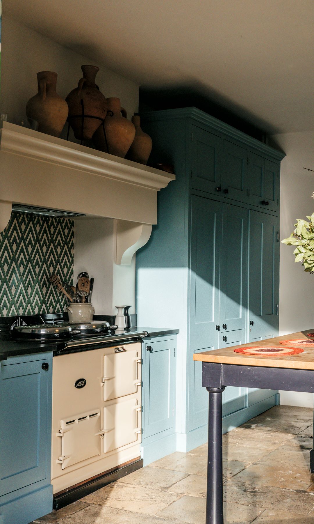 Cocina con gabinetes azules, estufa vintage, y jarrones decorativos en la repisa.