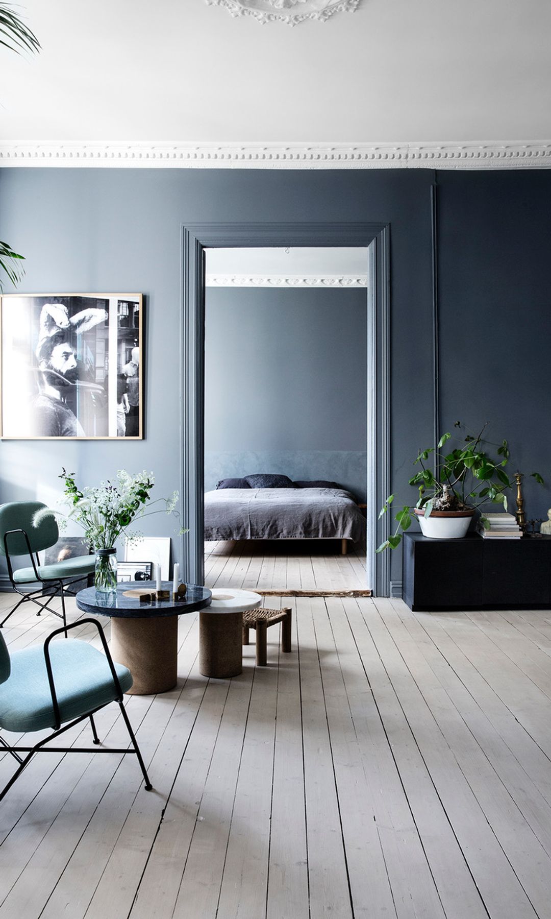 Salón de estilo nórdico con paredes grises, suelo de madera, butacas y mesa de centro, plantas