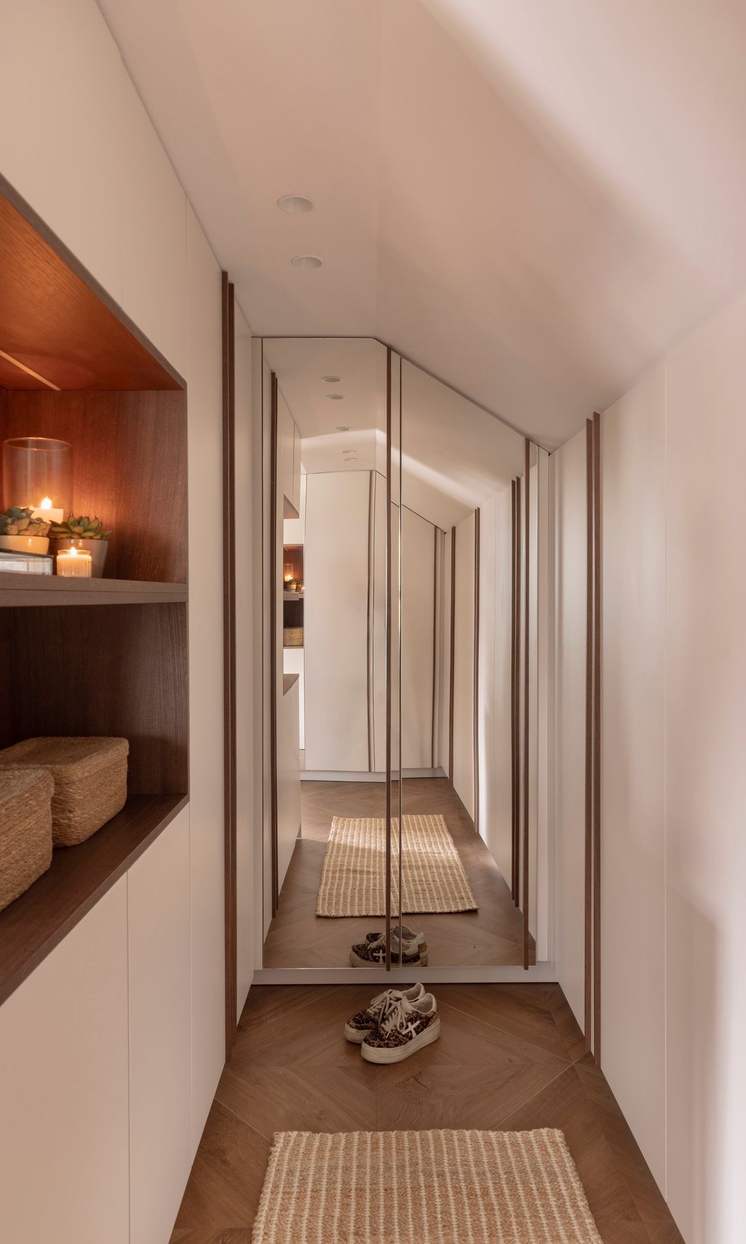 Vestidor abuhardillado con espejo, suelo de madera, zona abierta y zona de armarios blancos 