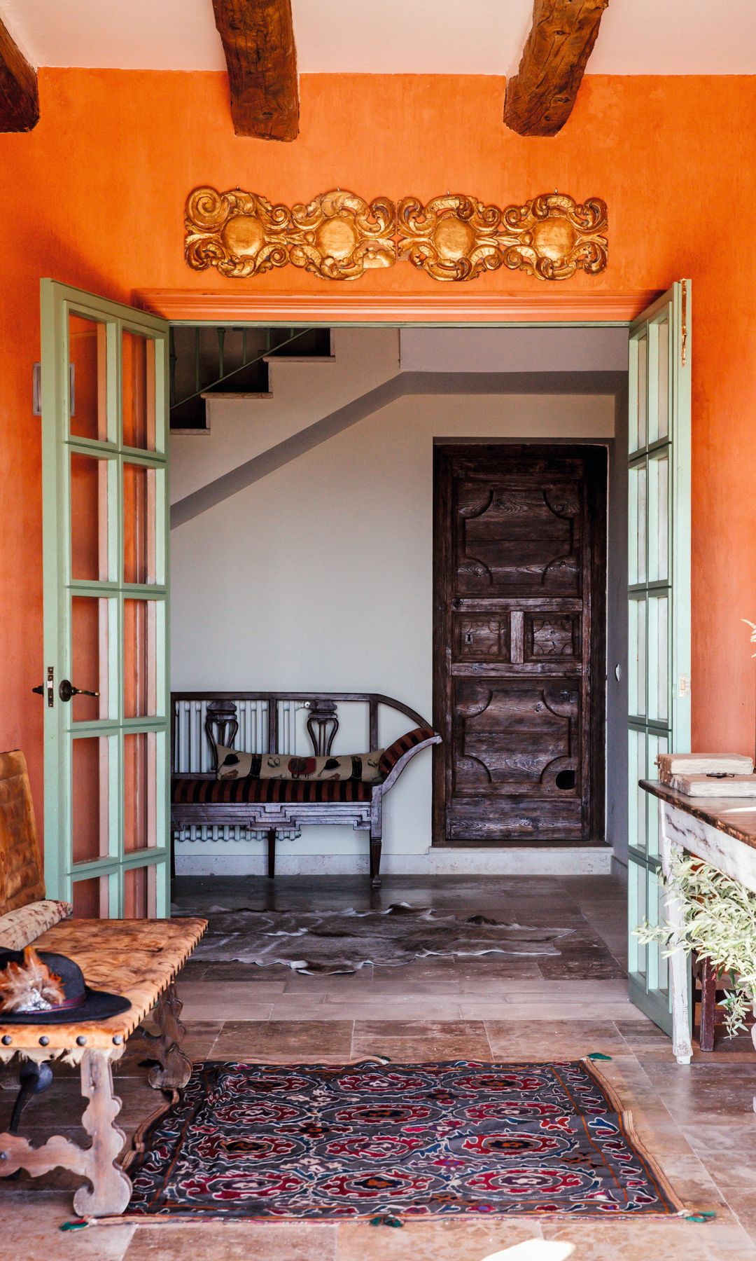 Dos imágenes del recibidor, en tonos naranjas, como la fachada de la vivienda