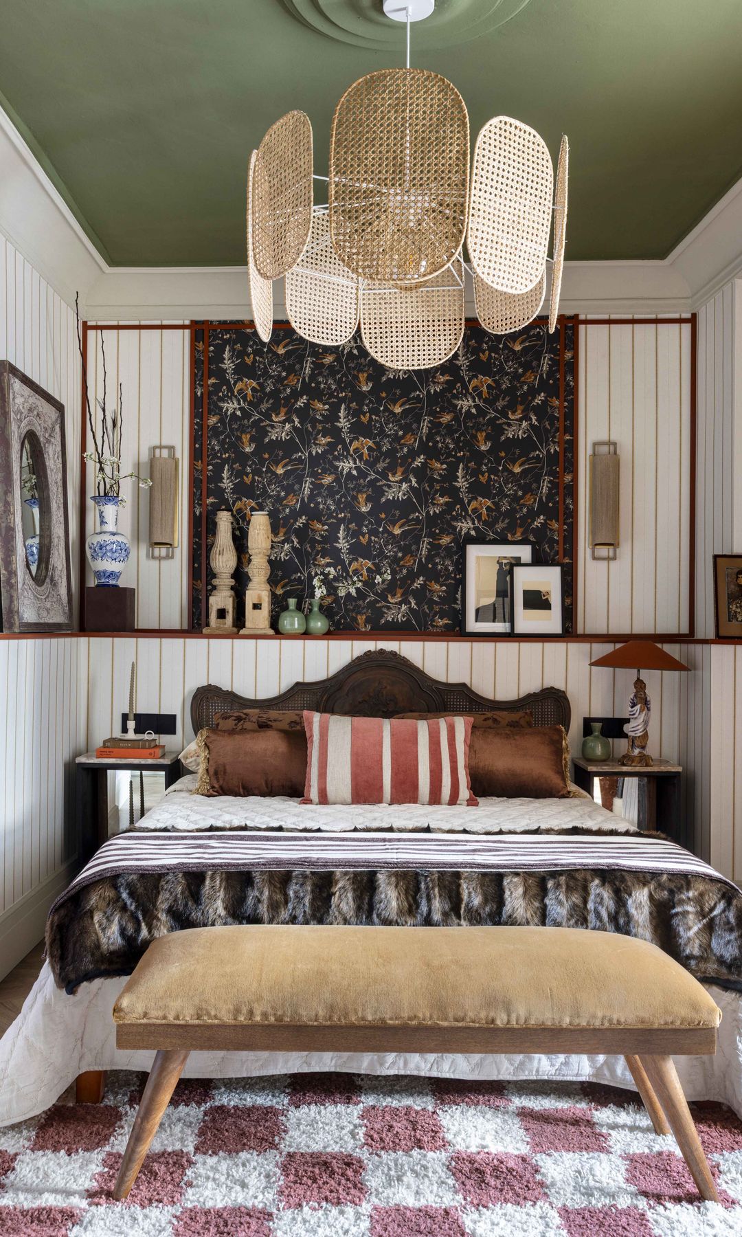 Dormitorio con paredes con lamas de madera blanca, techo verde, lámpara de techo de fibras vegetales, cabecero en pico, pared del cabecero con papel pintado, banqueta a los pies de la cama