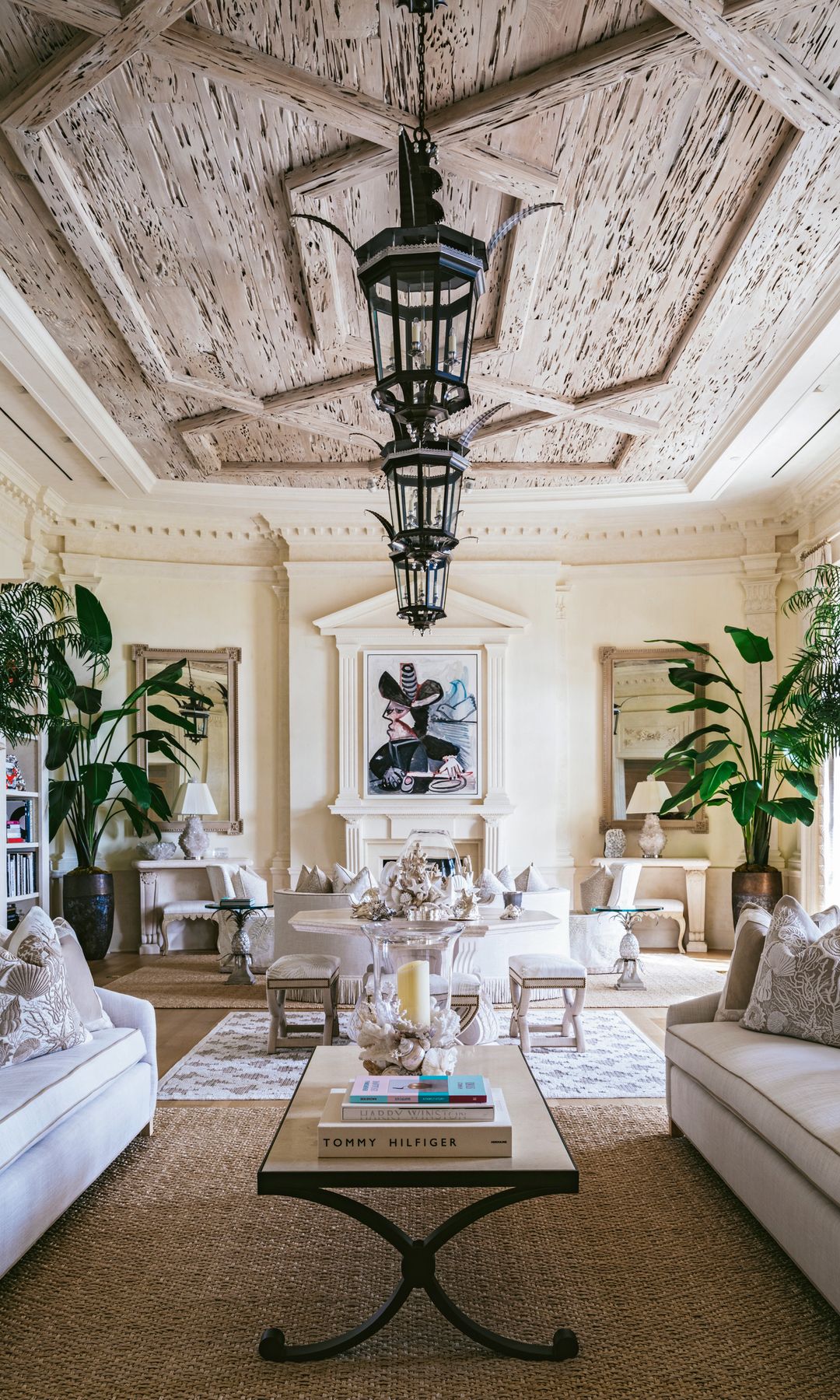 Salón con sillones blancoa y plantas y techo de madera con numerosas lámparas negras