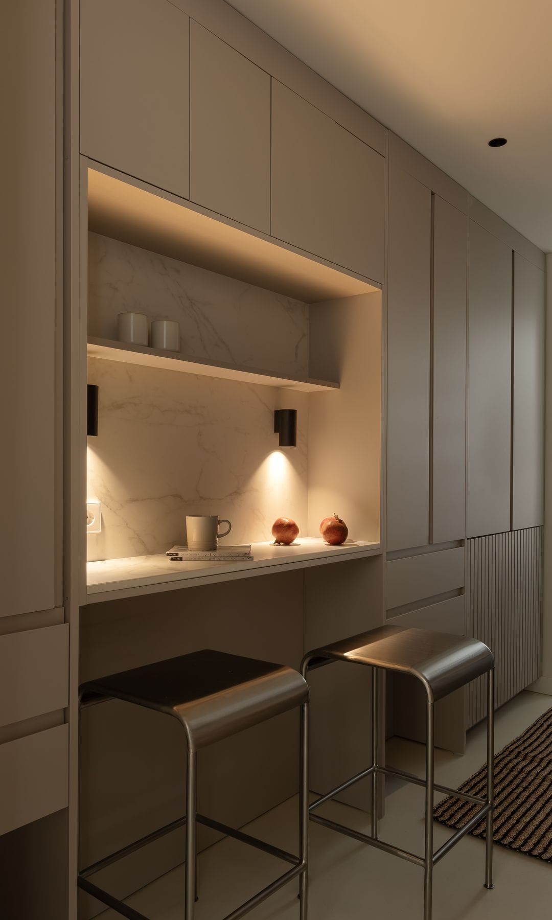 Cocina con frente de armarios y zona de desayunados con taburetes altos, apliques de pared