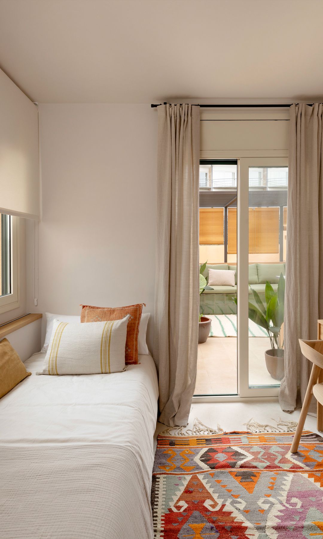 Habitación infantil con salida a terraza, cortinas beige, alfombra tipo kilim, escritorio, cojines en color tostado y blanco
