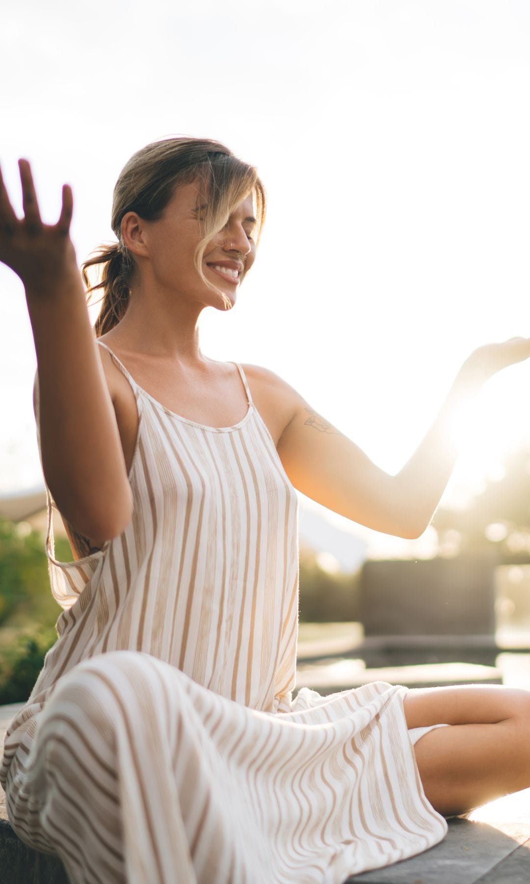 mujer sonriente haciendo yoga y meditación junto a una piscina 