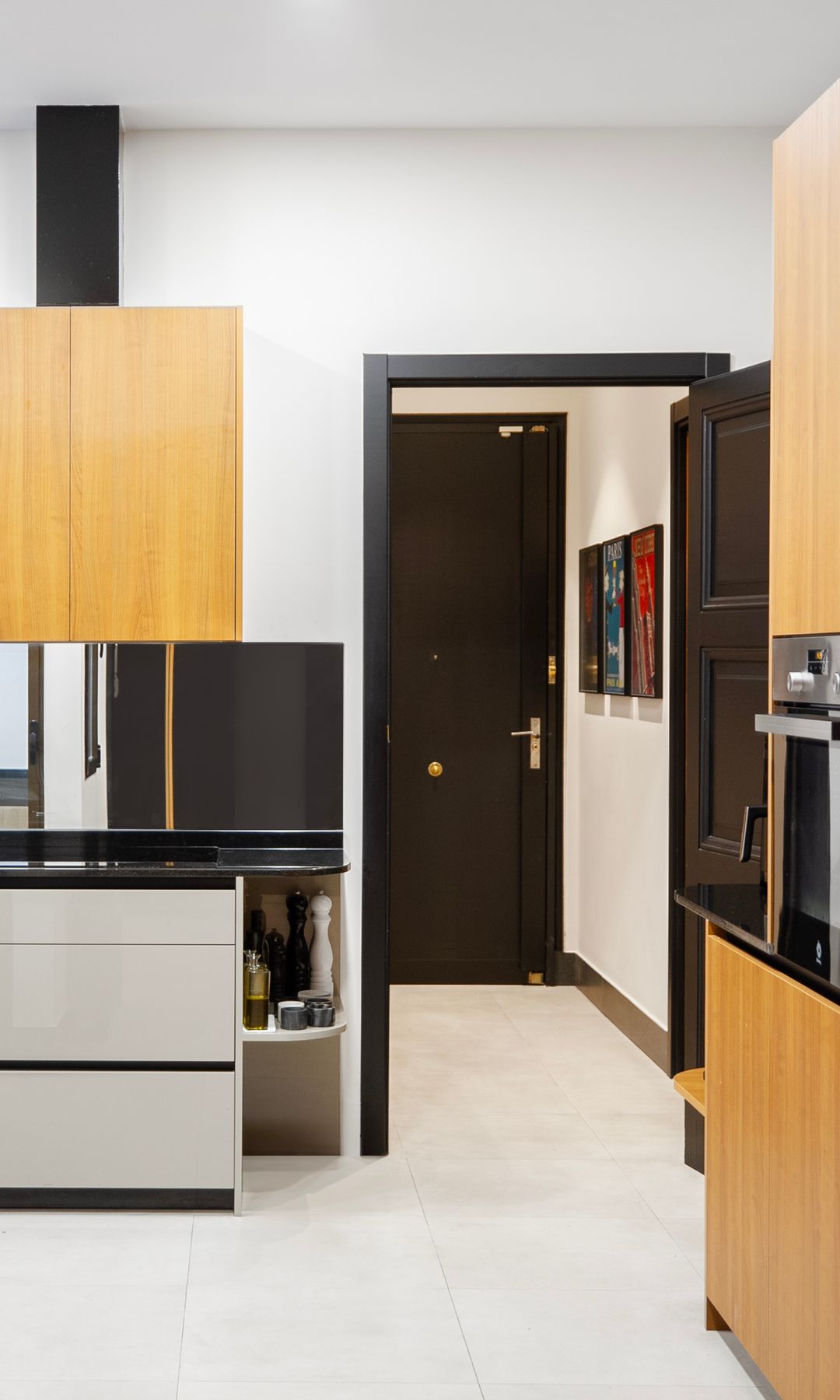 Cocina con muebles de madera, encimeras negras, puerta negra