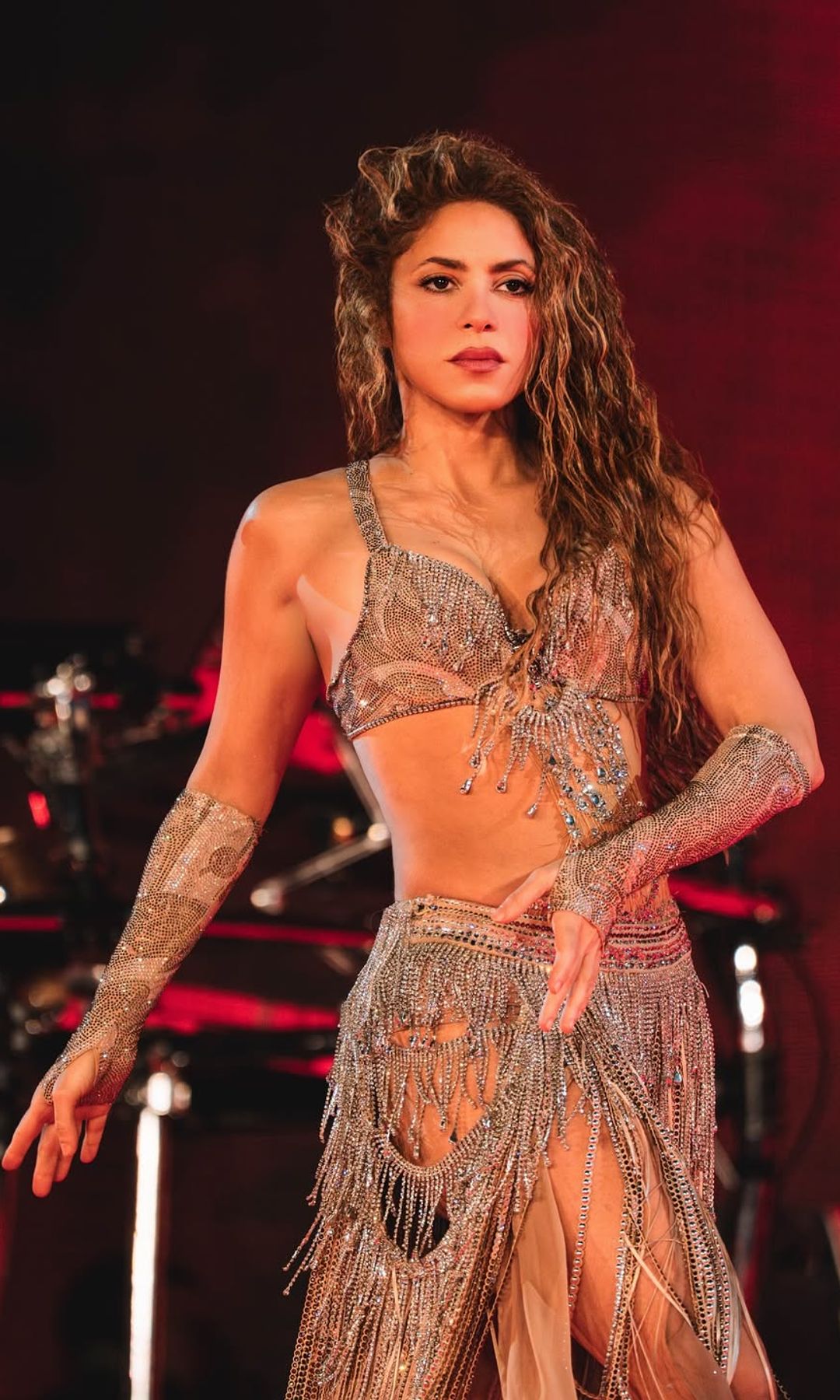 Shakira durante concierto con vestuario brillante y activación muscular en core y cadera