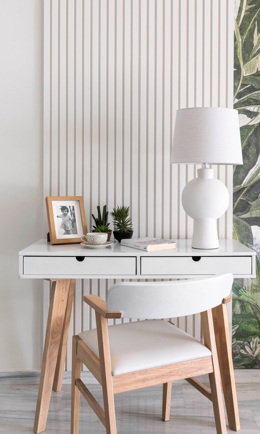 Escritorio blanco con dos cajones, silla blanca, mesa de sobremesa blanca, fotografías con marco de madera, papel pintado en la pared