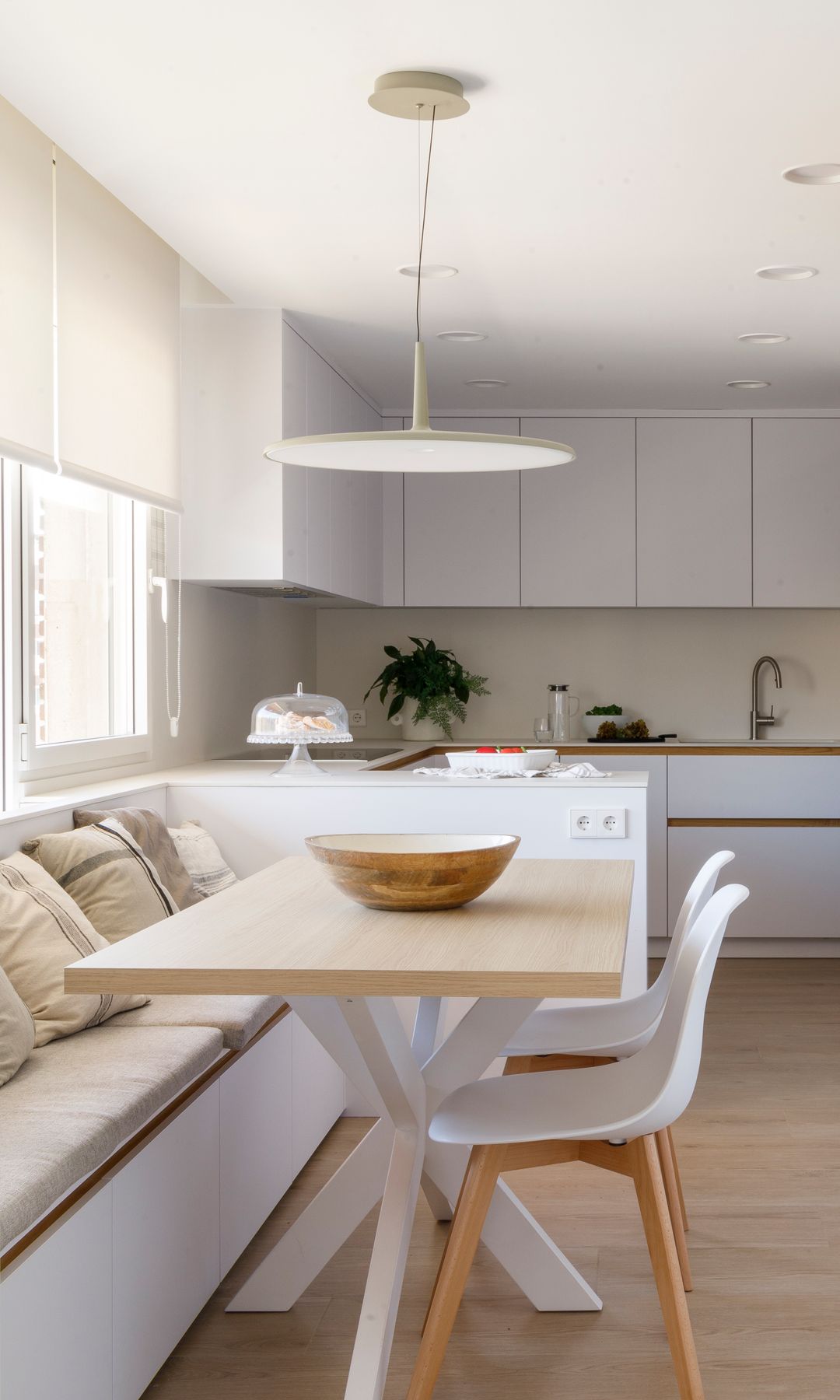 Cocina blanca con office, puerta corredera banco bajo la ventana, mesa de madera con patas blancas 