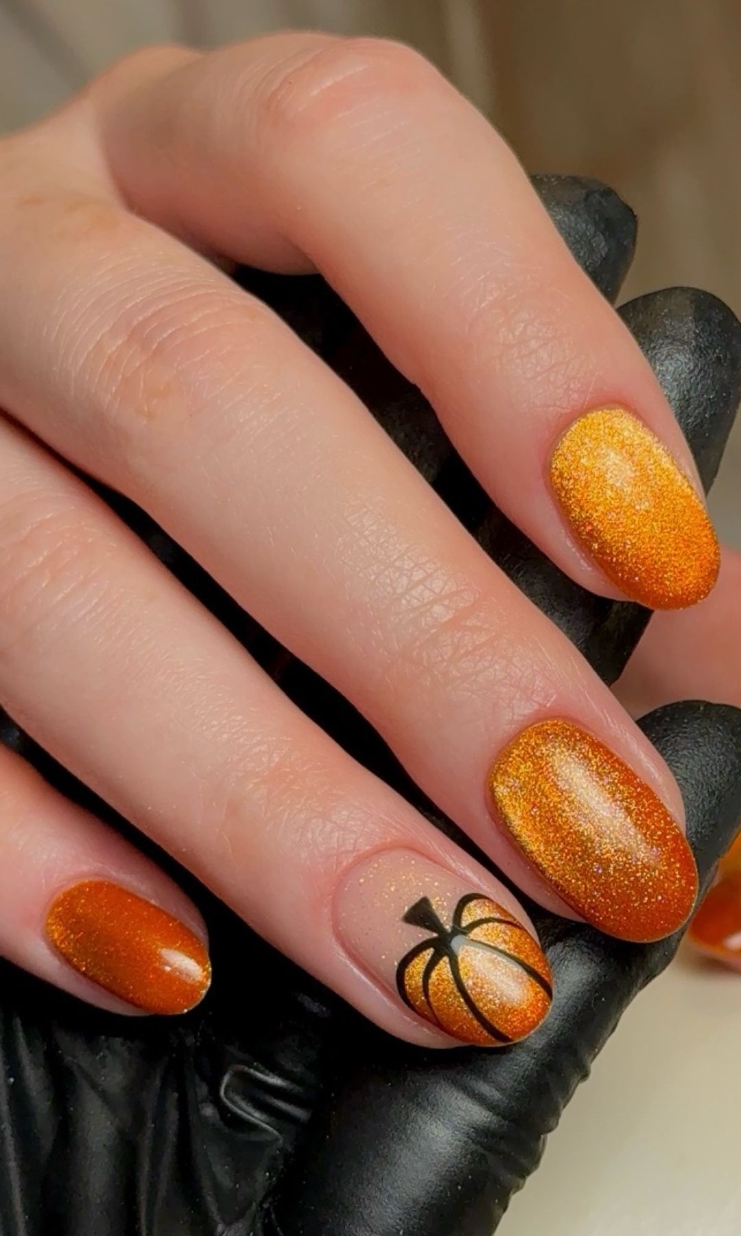 Manicura naranja con calabazas y efecto ojo de gato