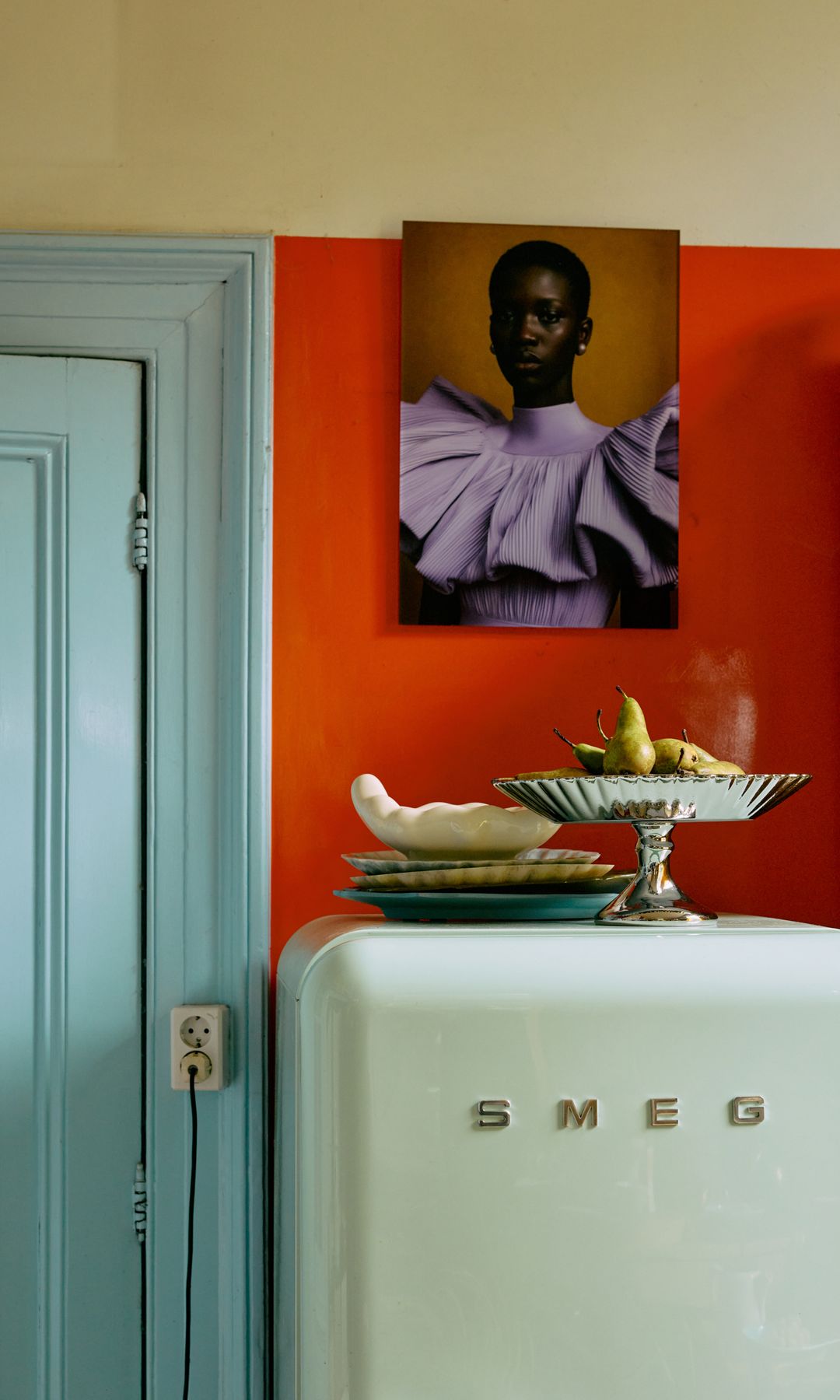 Cocina con nevera retro Smeg en color blanco, pared roja, fotografía, frutero sobre la nevera, platos