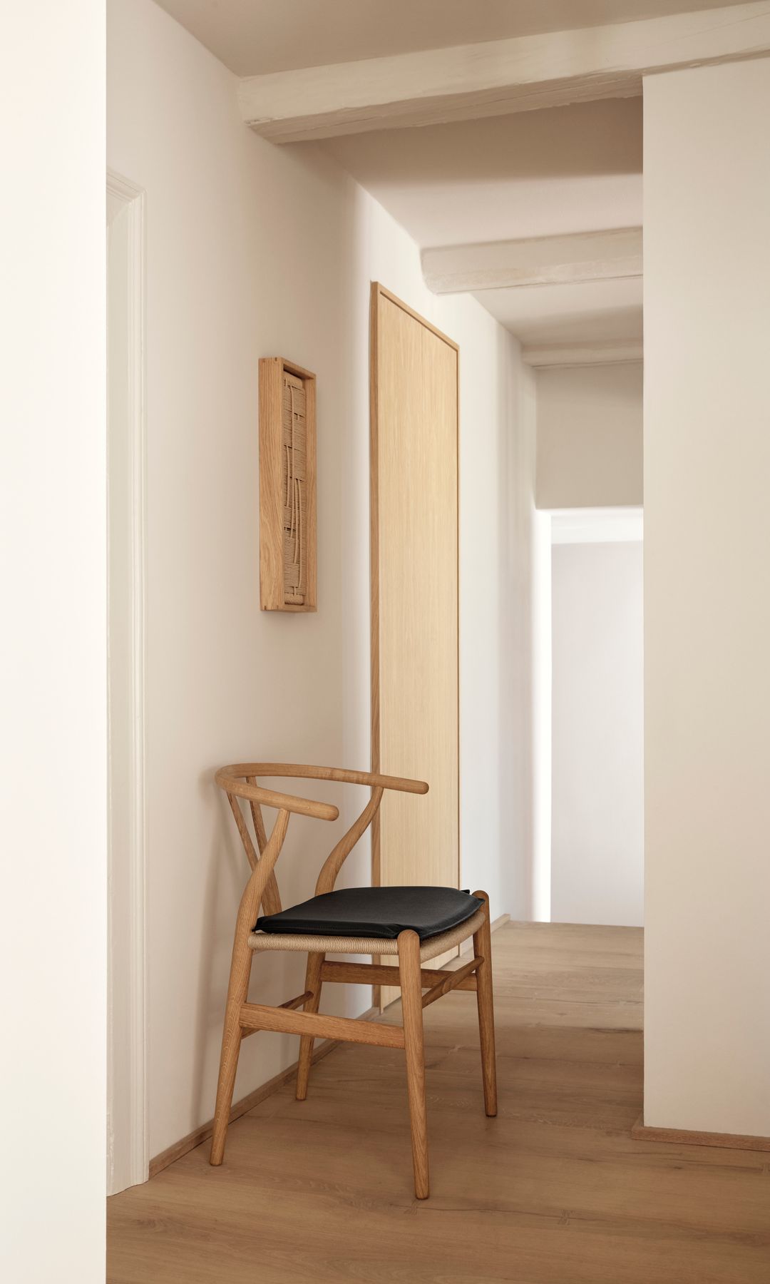 Pasillo con suelo de madera y silla de madera con asiento tapizado, cuadro