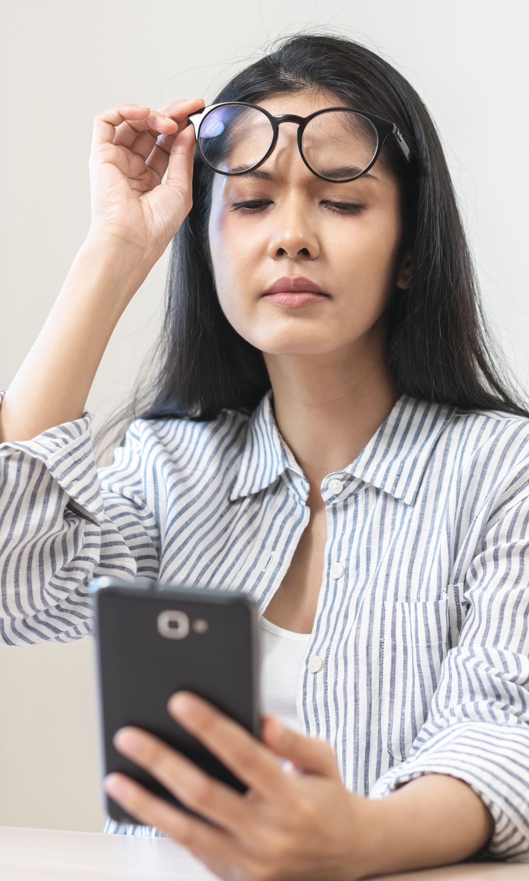 mujer mirando su móvil levantándose las gafas