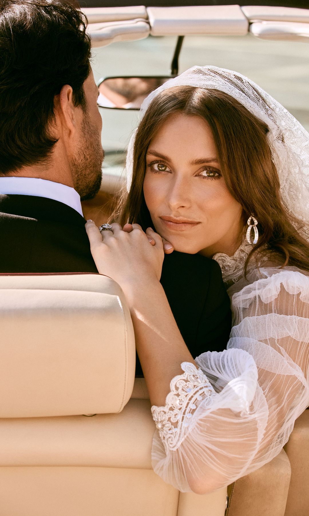 La modelo lleva vestido con mangas de gasa y detalles bordados en cuello y puños, de María Baraza; pendientes en oro blanco y diamantes, de Ansorena, y velo de encaje de Mimoki