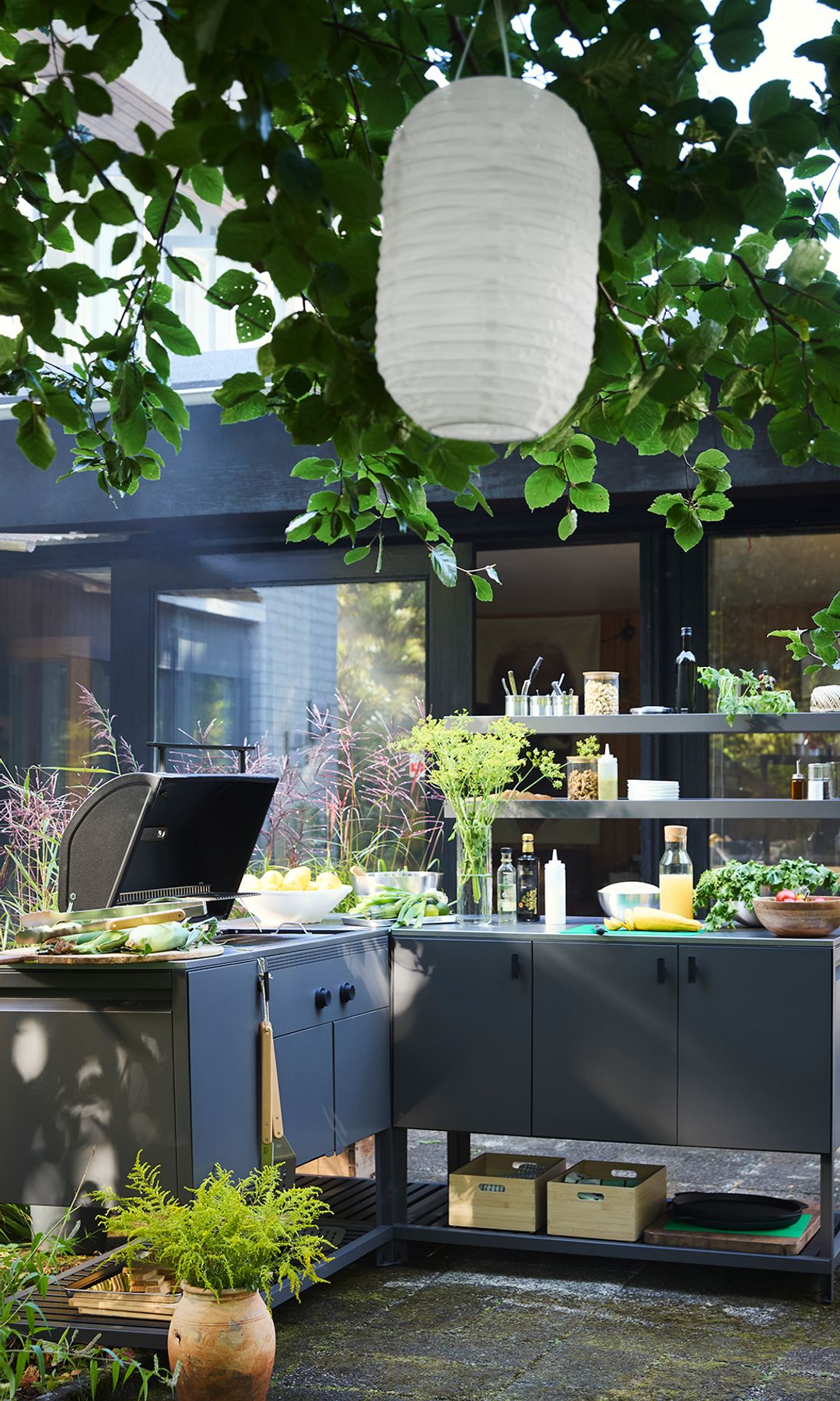 Jardín con cocina exterior IKEA, lámparas de papel y plantas