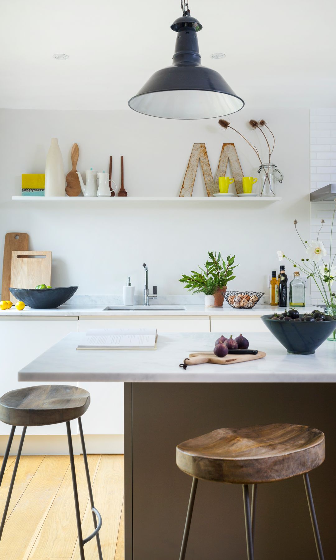 Cocina sin muebles altos, con baldas, paredes y muebles de color blanco, isla de cocina con taburetes altos 