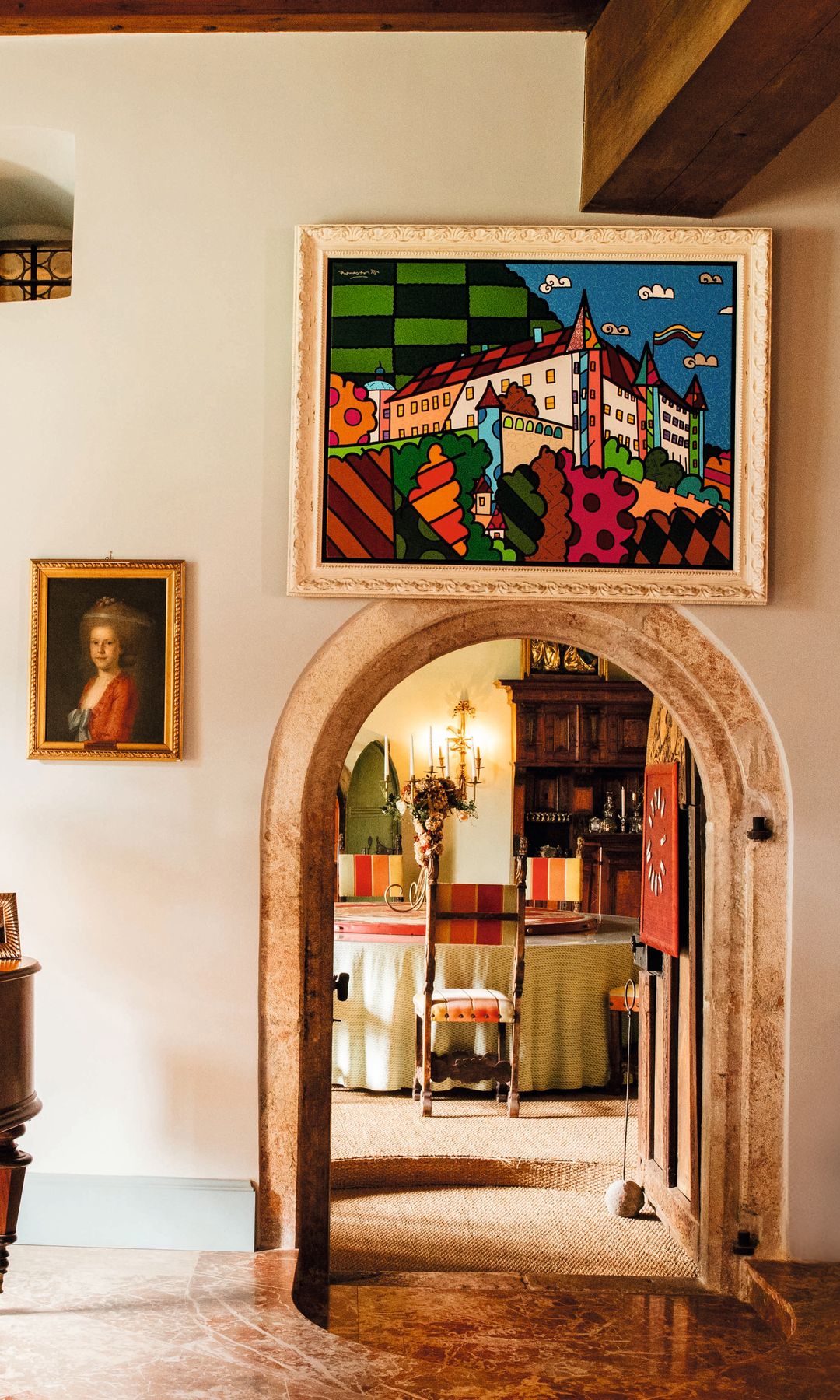 Una pintura moderna del castillo, firmada por Romero Britto en una sala con piano, cuadros, y sillón