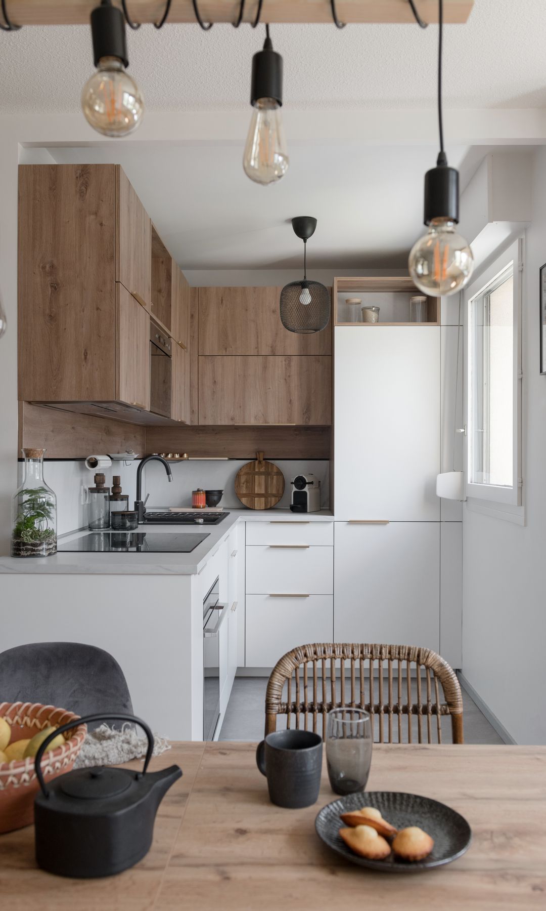 Cocina con comedor con muebles blancos y de madera, mesa de comedor de madera, lámpara de techo