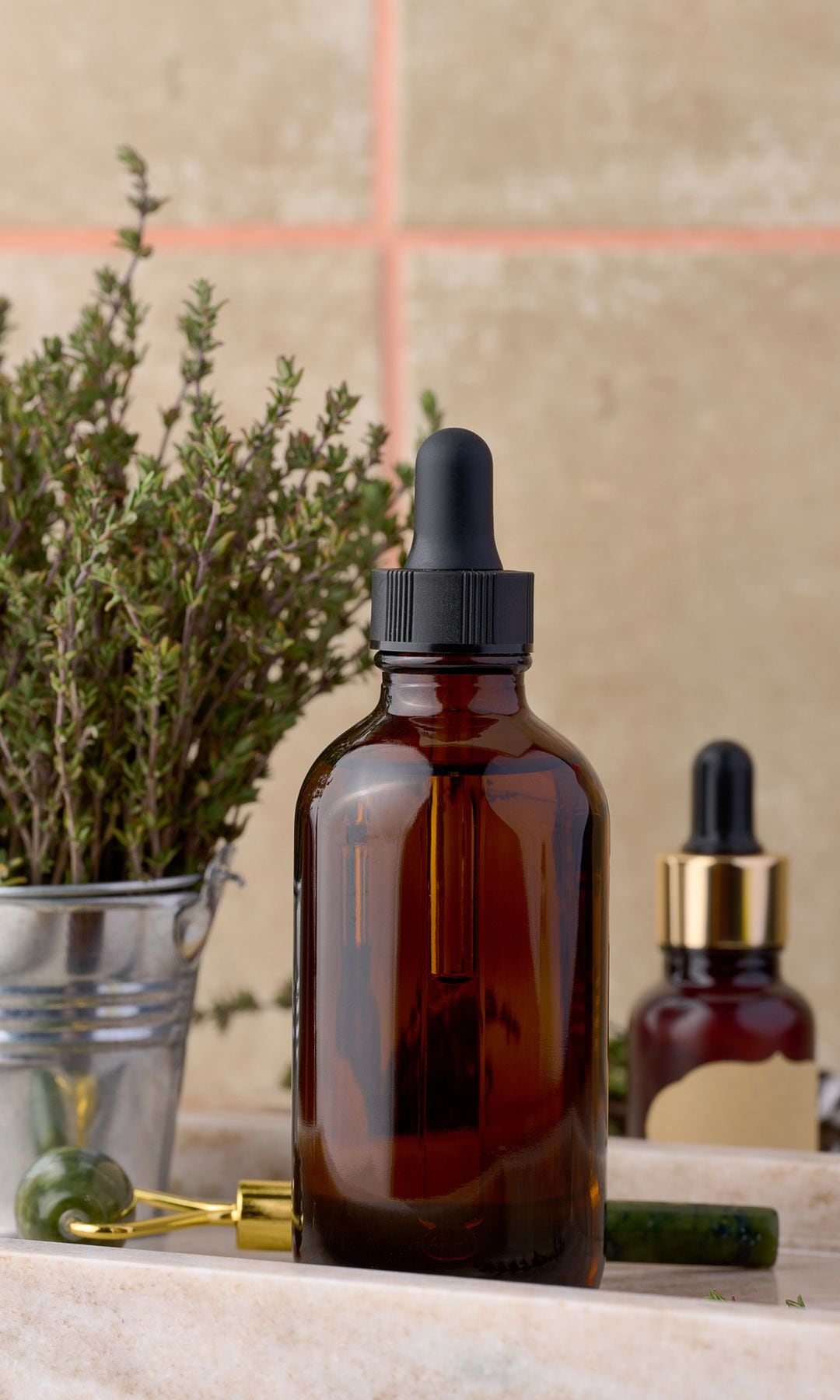 Aceite esencial de cirpés en una botella con dosificador sobre una mesa en la que hay algunas herramientas cosméticas