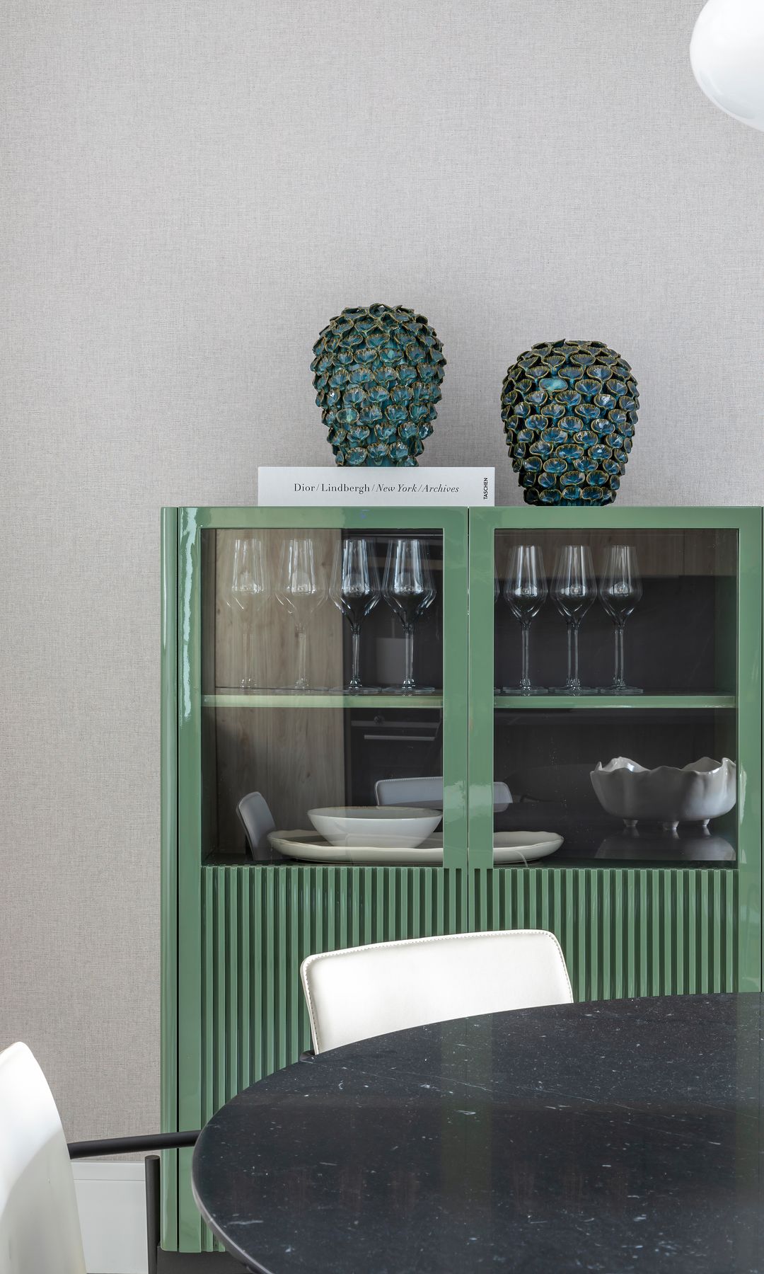 Vitrina de color verde con la parte de abajo cerrada y la de arriba abierta, con jarrones verdes