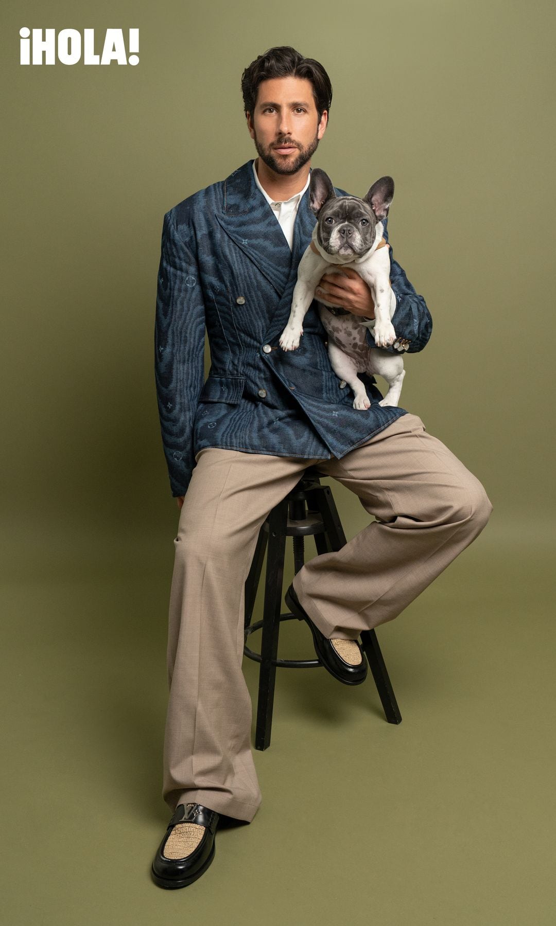 Con su característico estilo creativo y elegante, Diego posa con saco texturizado en azul, pantalones beige y camisa blanca. A su lado, Rufina luce un arnés reversible. Todo de Louis Vuitton.