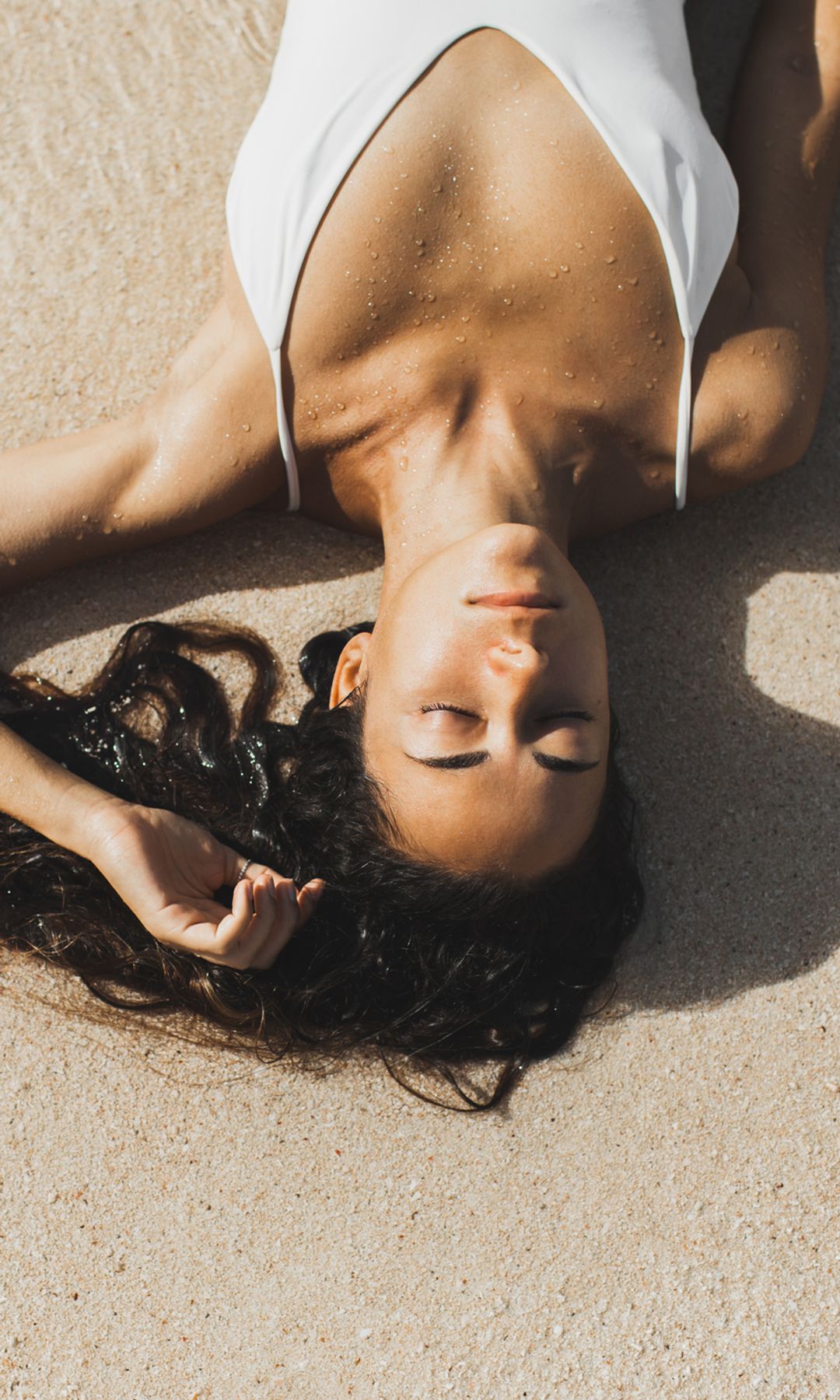 Mujer tumbada en la arena de la playa relajada