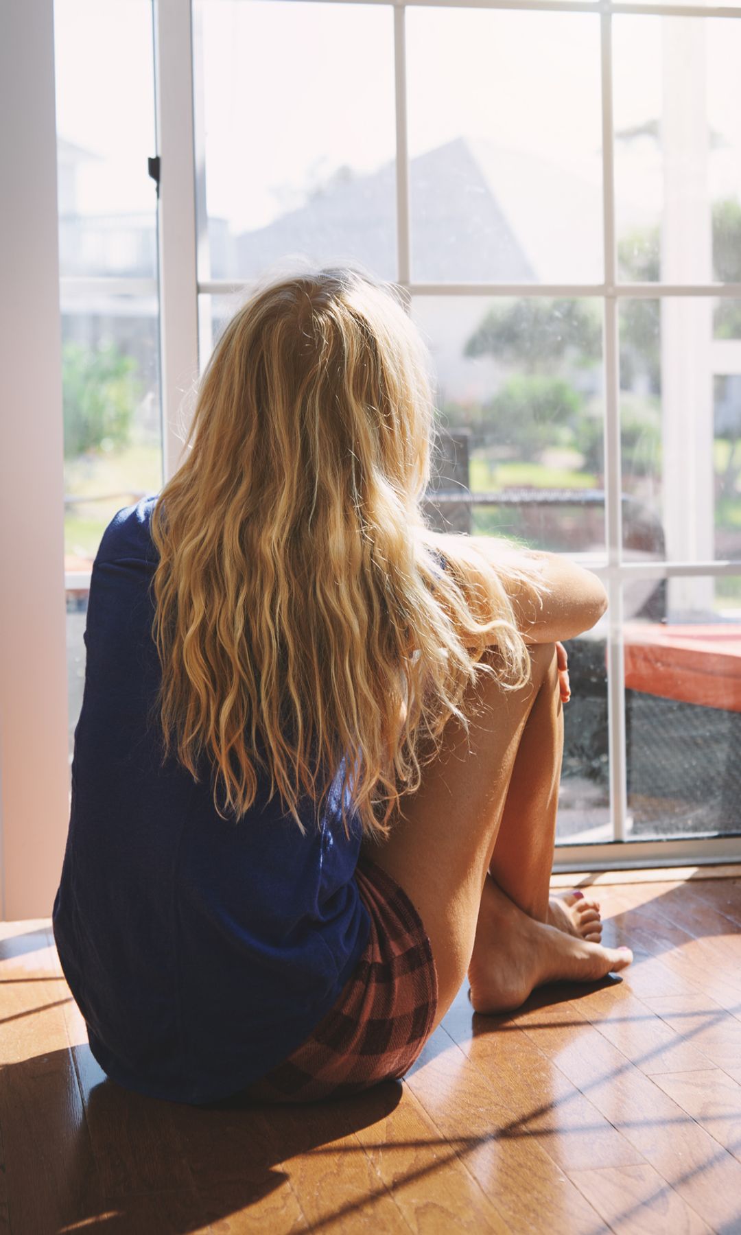 una mujer al sol frente a la ventana