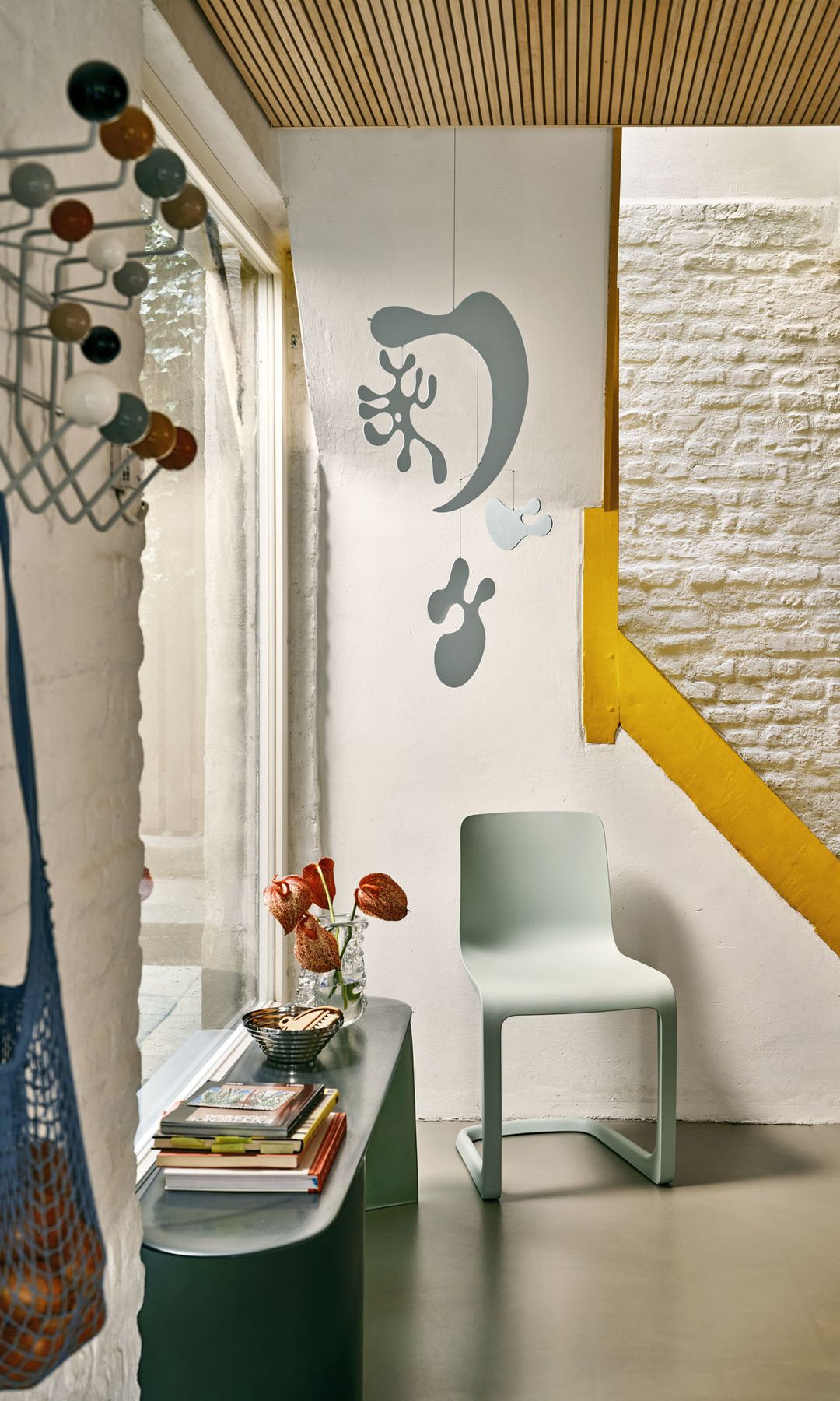 Recibidor con perchero de pared, mueble bajo con vaciacbolsillo, libros y jarrón, silla, dibujo en la pared