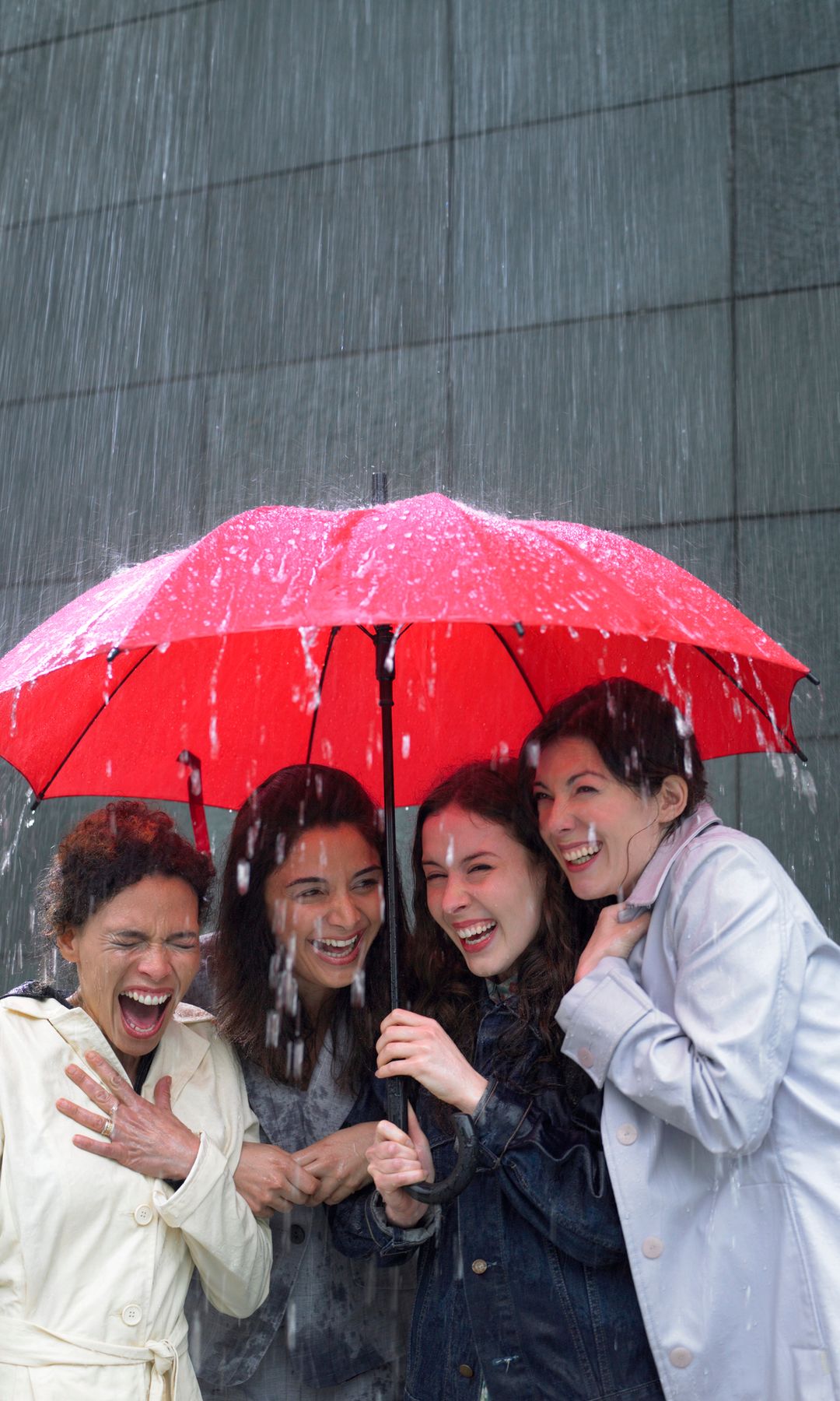 Amigas bajo la lluvia con un paraguas rojo 