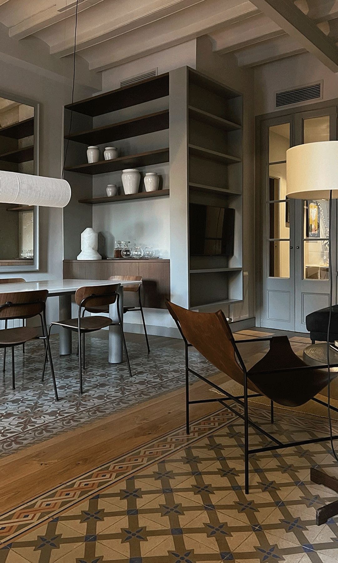 Salón comedor con suelos hidráulicos, lámparas de pie y de techo, vigas, butaca de cuero, 