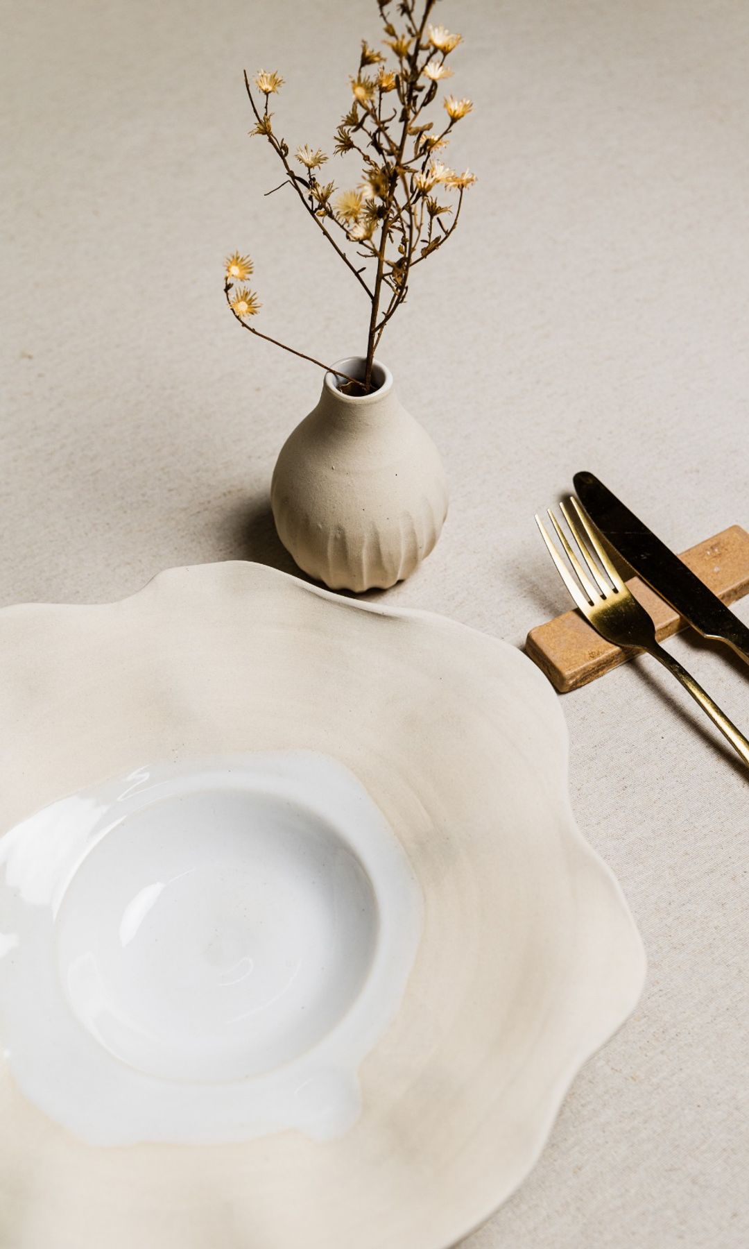 Plato de cerámica con jarrón y cubiertos dorados