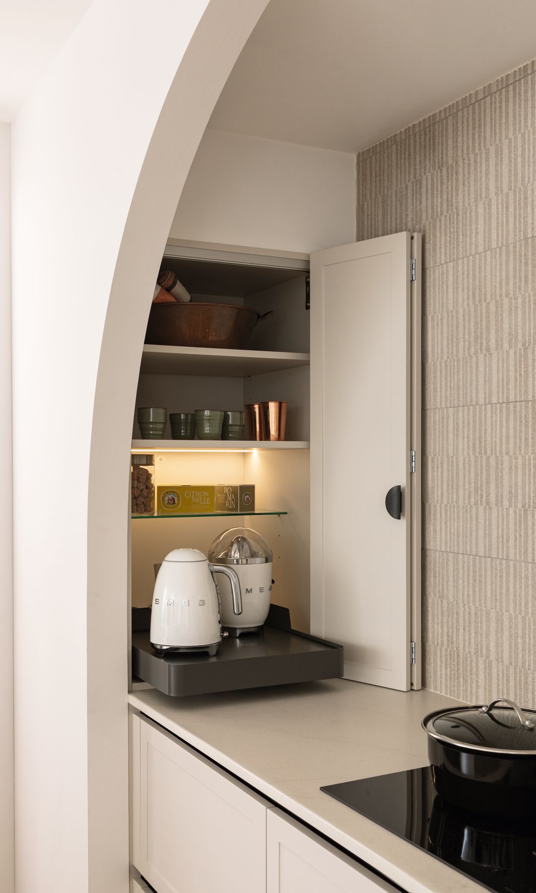 Mueble desayunador con puerta plegable y bandeja extraíble con tetera y exprimidor Smeg, baldas con tazas y paquetes de café